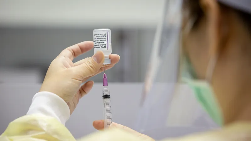 穿著防護衣的護理人員用針筒抽取疫苗