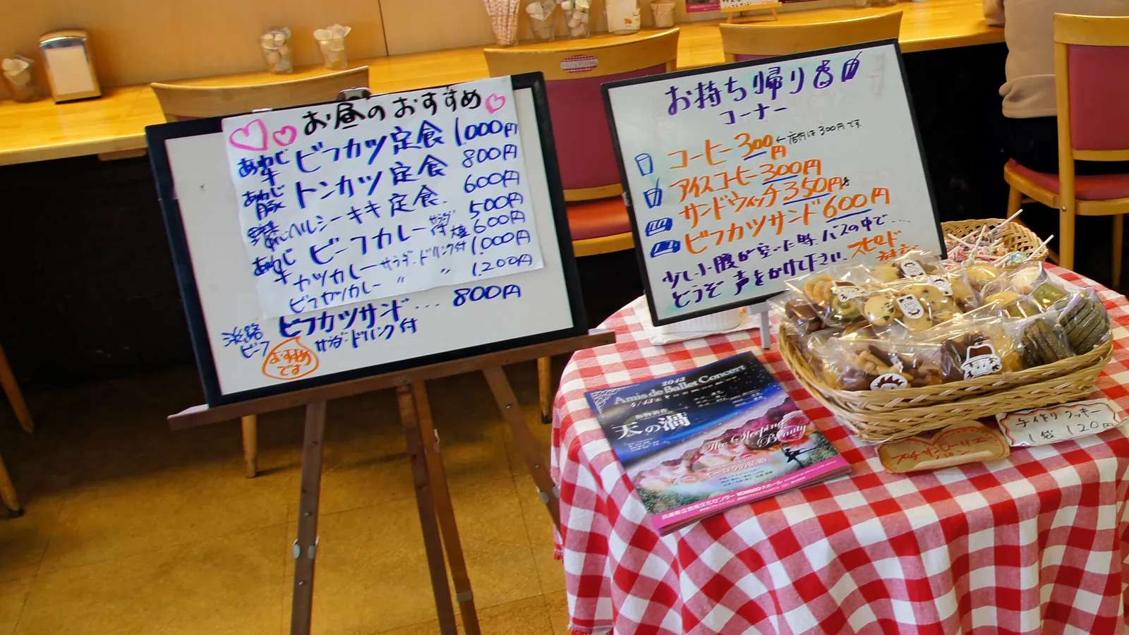 小店門口的手寫菜單白板與擺著外帶點心的紅格子桌